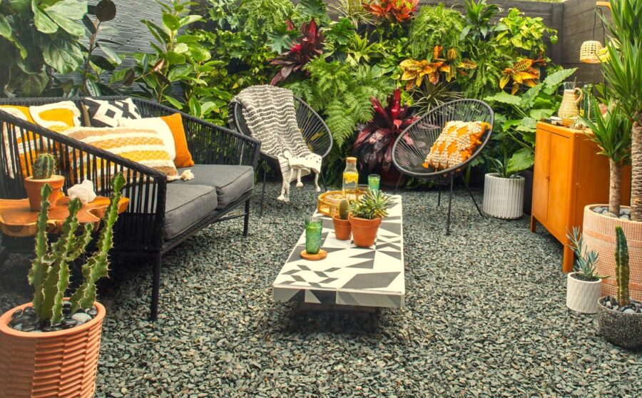 mini jardin con sillas y sofa de exterior con suelo de piedras grises